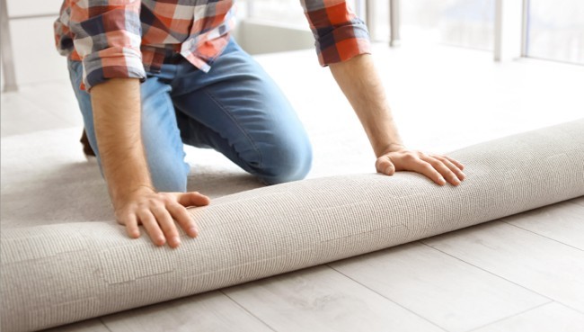 Man rolling carpet for installation | Rugs Rolls and More