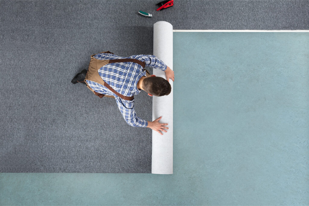 Man rolling carpet for installation | Rugs Rolls and More